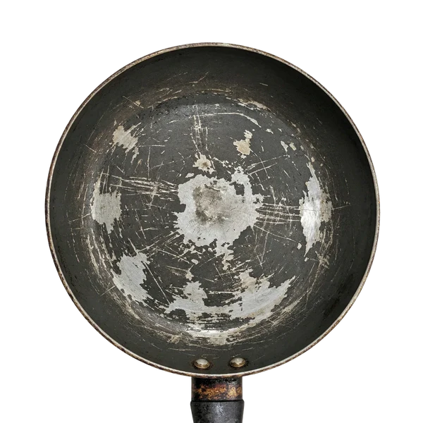 A worn nonstick skillet with scratches and flaking coating across the cooking surface